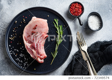 Raw Pork Loin chops in a black round plate on a 72349574