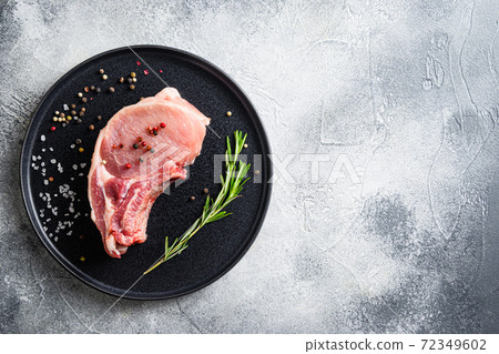 Pork chop on a bone in a black round plate on a 72349602