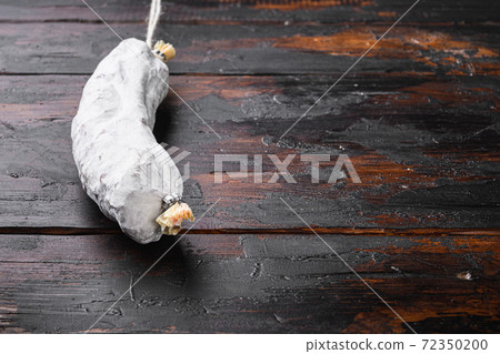 Spanish dry salchichon sausage on old wooden table 72350200