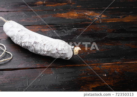 Spanish dry salchichon sausage on wooden surface 72350313