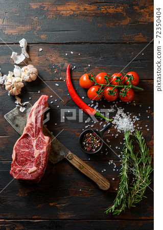 Raw dry steak cowboy on dark wooden vintage table 72350404