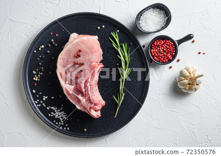 Raw Pork Loin chops in a black round plate on a 72350576
