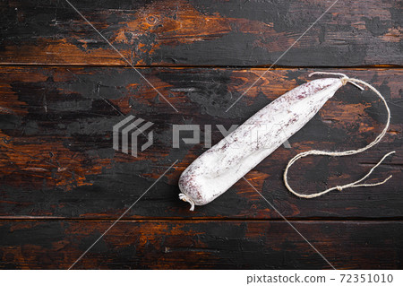 Dry cured longaniza sausage on old wooden table, 72351010