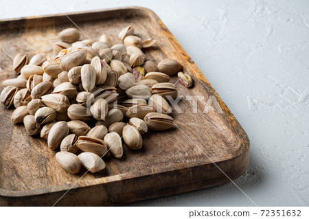 Shelled unsalted pistachios, on white textured background Shelled unsalted pistachios, on white textured background 72351632