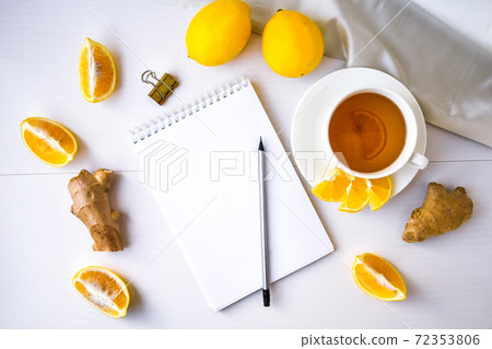 Trendy flat lay Ginger hot immunity boosting Vitamin natural drink With citrus lemon notebook and pencil on white background. Copy space 72353806