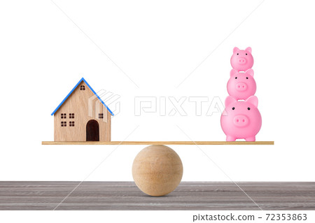 Model house on wooden seesaw balancing with stacking saving piggy bank on white background. Property investment and home mortgage financial real estate advertising concept 72353863