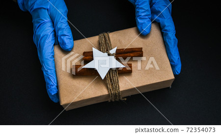 Holiday shopping. Festive gifts. Pandemic restriction. Winter shopping. Hand in protective gloves holding present zero waste box. Advertising background. Pandemic. Stay safe. Holiday shopping. Festive gifts. Pandemic restriction. Winter shopping. Hand in protective gloves holding present zero waste box. Advertising background. Pandemic. Stay safe. 72354073