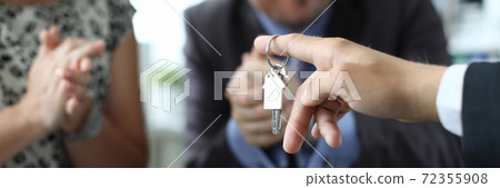 Husband and wife receive key to apartment from seller in office closeup 72355908