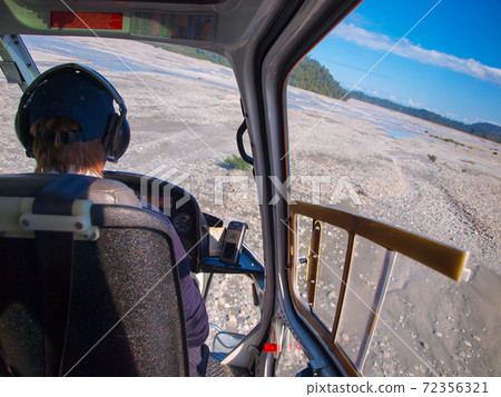 Helicopter cockpit view over broad river bed 72356321