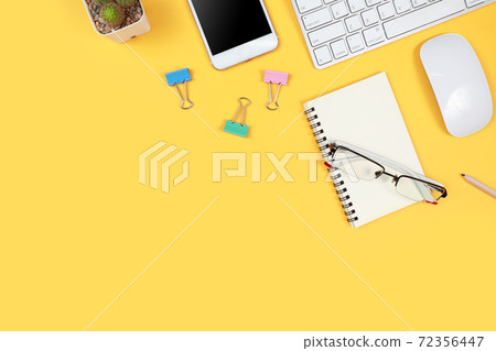 workspace table with laptop computer, office supplies, coffee cup, cell phone and coffee cup on yellow background 72356447