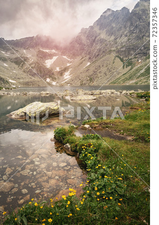 The lake is surrounded by the mountains which are reflected in the water. 72357346