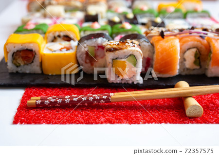 Wooden chopsticks on a red mat in the foreground. Wooden chopsticks on a red mat in the foreground. 72357575
