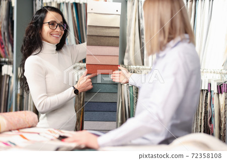 Woman choosing color of fabric from many samples in store Woman choosing color of fabric from many samples in store 72358108