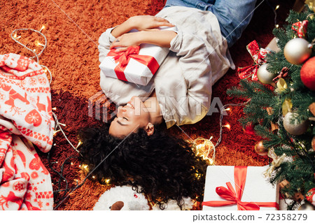 Beautiful brunette woman lies at the Christmas tree with lights garlands new year Beautiful brunette woman lies at the Christmas tree with lights garlands new year 72358279