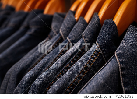 Selective focus on jacket jeans hanging on rack in clothes shop. Denim jeans with jeans pattern. Textile industry. Jeans fashion and shopping concept. Clothing concept. Denim jacket on rack for sale. 72361355