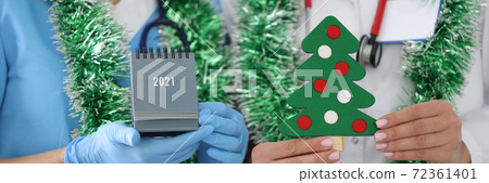 Nurse with white coat hold paper Christmas tree with decorations. Nurse with white coat hold paper Christmas tree with decorations. 72361401