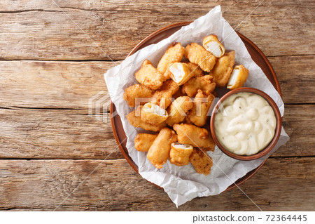 Tasty Kibbeling is a Dutch dish prepared with pieces of cod served with sauce closeup in the plate. Horizontal top view 72364445