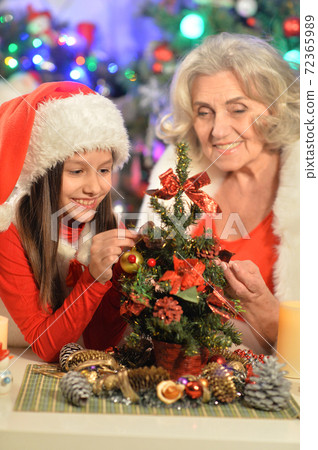 Smiling little girl with grandmother preparing for Christmas 72365989