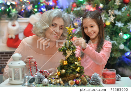 Smiling little girl with grandmother preparing for Christmas Smiling little girl with grandmother preparing for Christmas 72365990