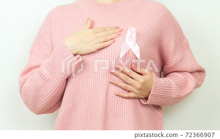 Pink badge ribbon on woman chest to support breast cancer cause. Medicine, healthcare and breast cancer awareness concept 72366907