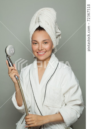 Smiling woman in white bathrobe holding shower and singing Smiling woman in white bathrobe holding shower and singing 72367518