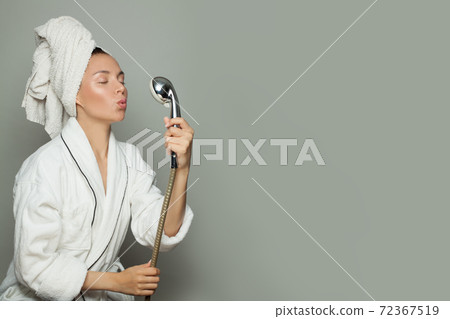 Pretty happy woman wearing white bathrobe with a shower and singing Pretty happy woman wearing white bathrobe with a shower and singing 72367519