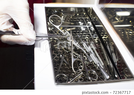 The girl takes out various metal instruments from the electronic sterilizer. Preparation for work. Disinfection of items for the work of a nail salon 72367717