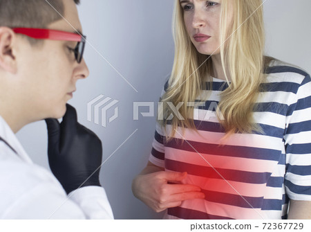 A woman holds on to his stomach. Pain in the abdominal cavity. The concept of diseases of the stomach and digestive system. The doctor will palpate to find out the source of the pain 72367729