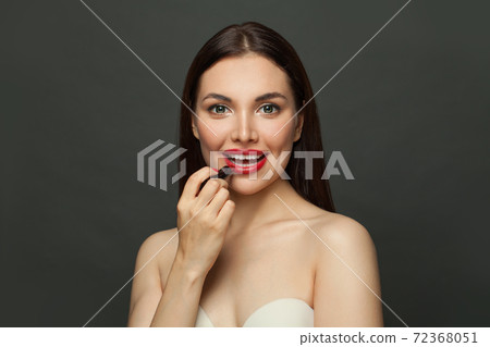 Lovely woman applying red lipstick on lips on black background 72368051