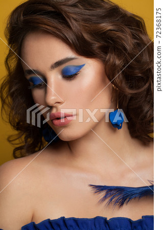 Elegant woman with brown curly hairstyle and makeup on yellow background Elegant woman with brown curly hairstyle and makeup on yellow background 72368175