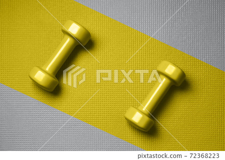 Yellow color dumbbells on the gray mat Yellow color dumbbells on the gray mat 72368223