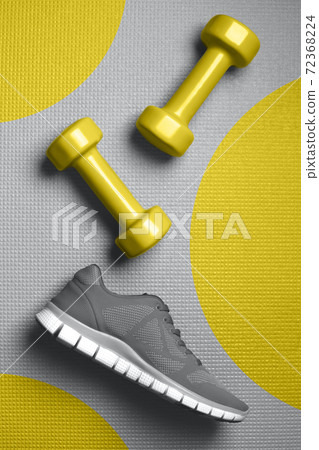 Yellow color dumbbells and gray color sneakers on the mat Yellow color dumbbells and gray color sneakers on the mat 72368224