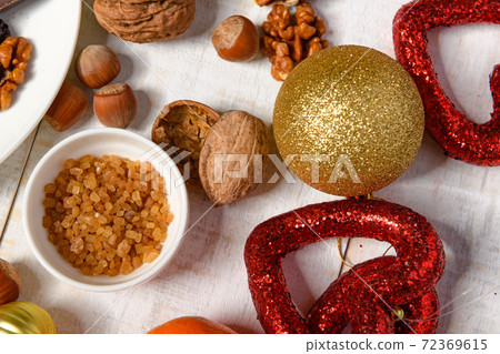 sweet food background for christmas or holiday decoration - chocolate candies, tangerines, nuts and dried fruits on white wood 72369615