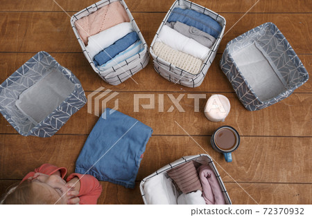 A group of organic cotton clothing laid out on a wooden background is ready to be folded into white baskets.The concept of closet organization.using the komari method. 72370932