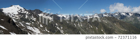 Panoramic view from Simmingjochl mountain saddle on sharp snow-capped peaks at Stubai hiking trail, Stubai Hohenweg, Alpine landscape of Tyrol, Stubai Alps, Austria. Summer blue sky 72371116