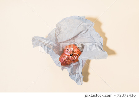 Top view retro vintage bauble in paper package on Set Sail Champagne background. Ussr Christmas  Top view retro vintage bauble in paper package on Set Sail Champagne background. Ussr Christmas  72372430