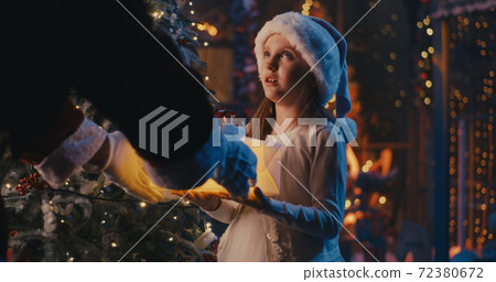 Crop Santa Claus giving present to cute girl Crop Santa Claus giving present to cute girl 72380672