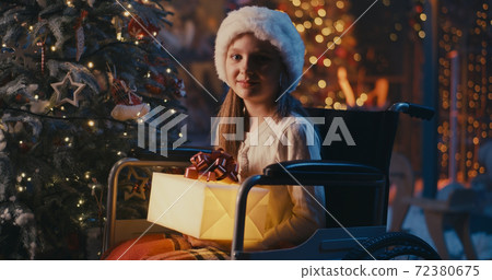 Astonished handicapped girl receiving gift from Santa Claus Astonished handicapped girl receiving gift from Santa Claus 72380675