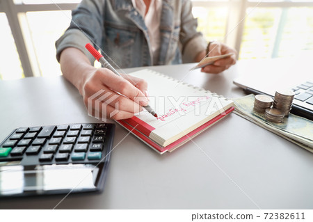businesswoman writing down monthly payment list on notebook with computer and credit card businesswoman writing down monthly payment list on notebook with computer and credit card 72382611