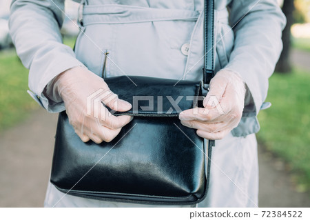 A girl in medical gloves opens a black leather bag A girl in medical gloves opens a black leather bag 72384522