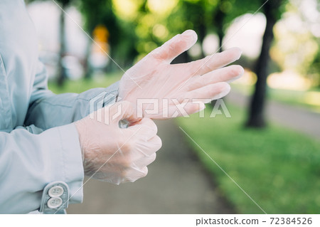 Young girl puts on medical protective gloves in the city Young girl puts on medical protective gloves in the city 72384526
