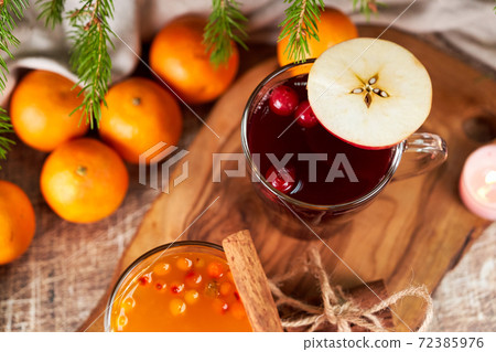 Red and yellow mulled wine in glass mugs and tangerines on the christmas table Red and yellow mulled wine in glass mugs and tangerines on the christmas table 72385976