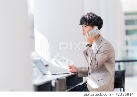 一個年輕的商人在辦公室打電話 72386914