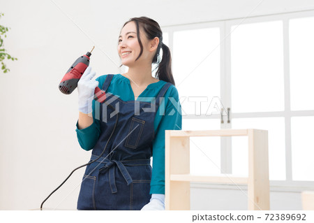 DIY girls who are pleased with the completion of the work with an electric drill in one hand DIY girls who are pleased with the completion of the work with an electric drill in one hand 72389692