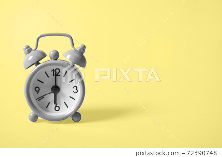 Analogue gray clock on yellow background. 72390748