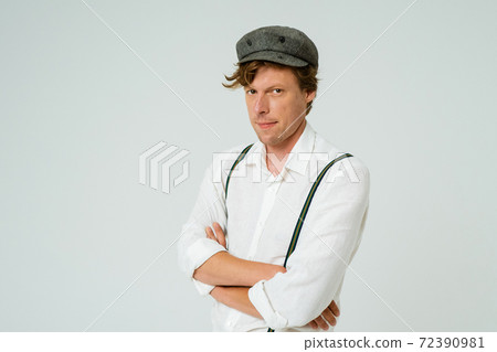 Hipster man posing with hands folded dressed in white shirt and grey wool cap isolated on white background. Copy space at left side 72390981