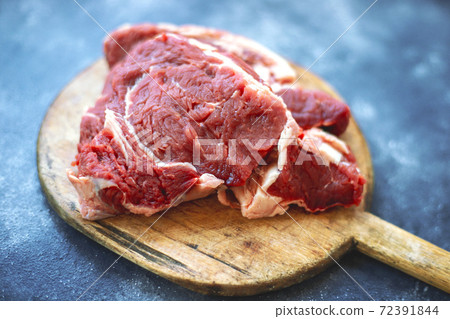 Raw meat beef steak on wooden cutting board on bluish black background. Top view. Close up. 72391844