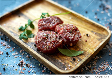 Raw meat beef steak on wooden tray, coarse pink Himalayan salt, black pepper, bay leaf, cilantro 72391853