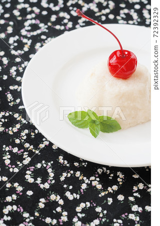 air white mousse dessert on a plate decorated with a cherry and mint on a black background with hearts 72392329