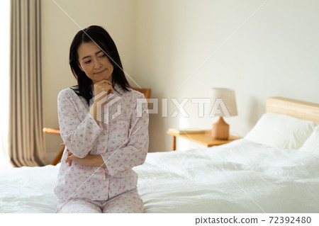 Woman thinking in the bedroom Woman thinking in the bedroom 72392480